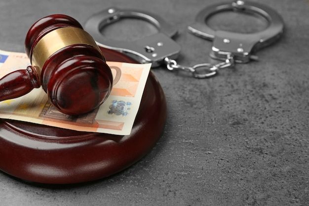 Фото Молоток закона с евро и наручниками на сером столе, крупным планом