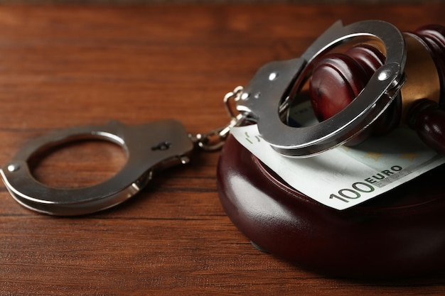 Law gavel with euro and handcuffs on wooden table background closeup