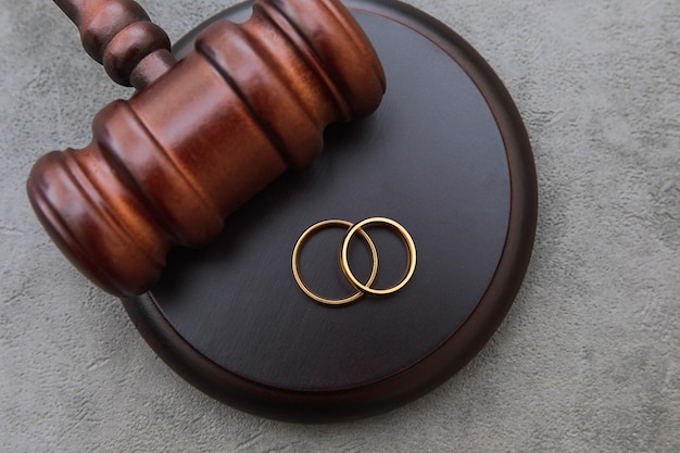 Photo law theme judge gavel wedding rings on concrete stone grey background divorce proceedings mallet of