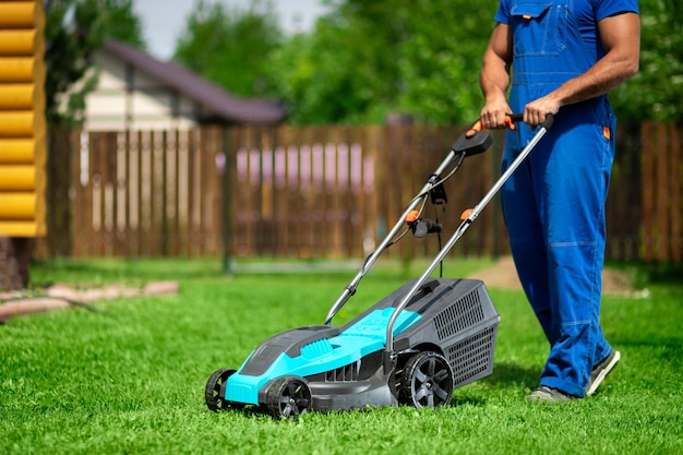 lawn grass mowing. worker cutting grass in a green yard. a man with an electric lawn mower mowing