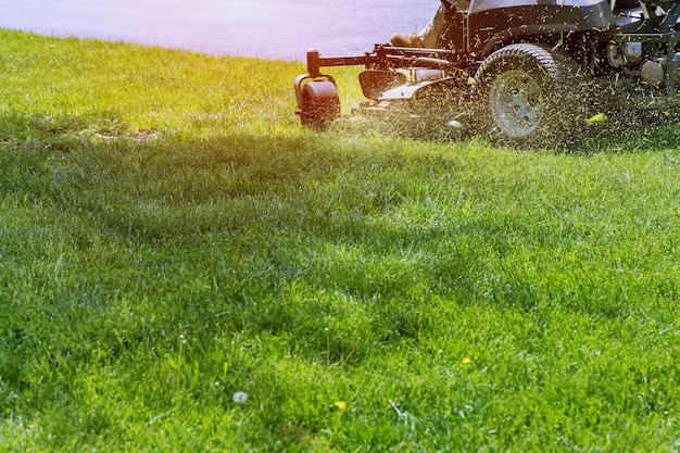 通り沿いのガーデニングで緑の草を刈る芝刈り機