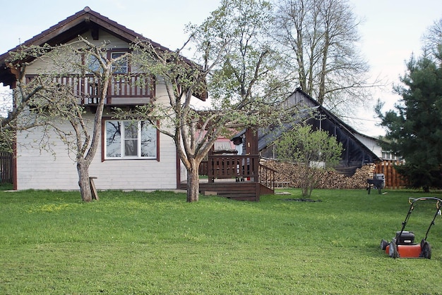 Photo lawn near the house old wooden house with trees in a green garden