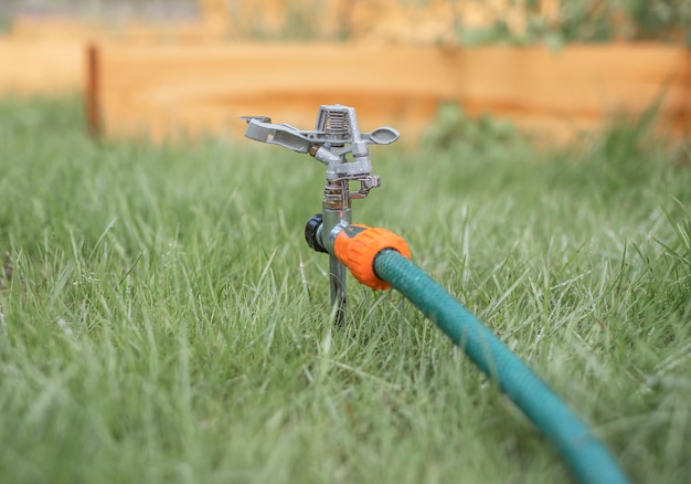 Lawn sprinkler in green grass turned off in summer