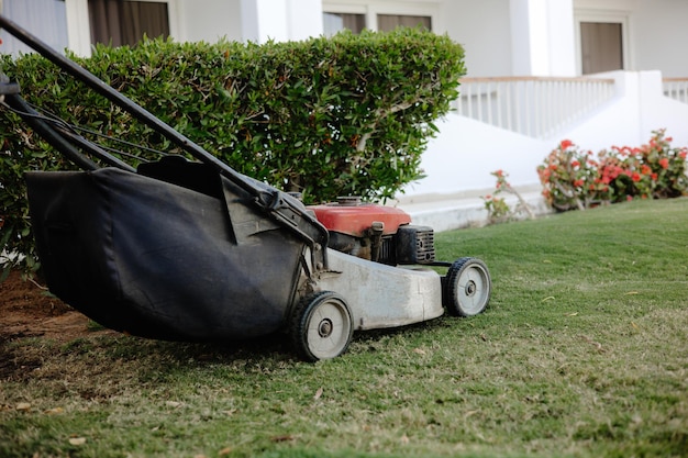 A lawnmower is being used to mow the grass in front of a house.