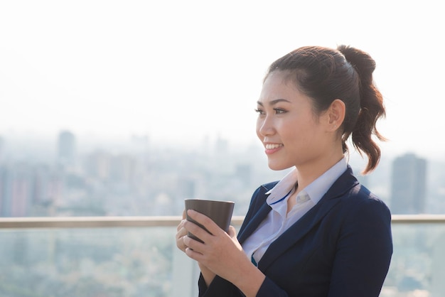 Lawyer businesswoman professional walking outdoors drinking coffee from disposable paper cup. Multiracial Asian / Caucasian businesswoman smiling