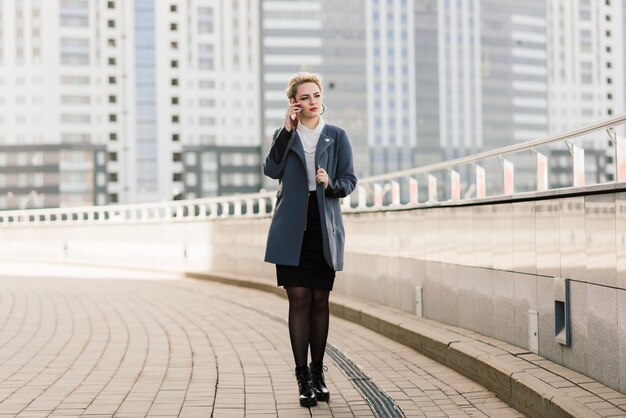 Lawyer businesswoman professional walking outdoors talking on cell smart phone drinking coffee from disposable paper cup.