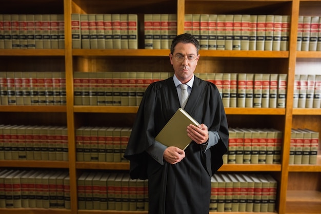 Адвокат, держащий книгу в юридической библиотеке