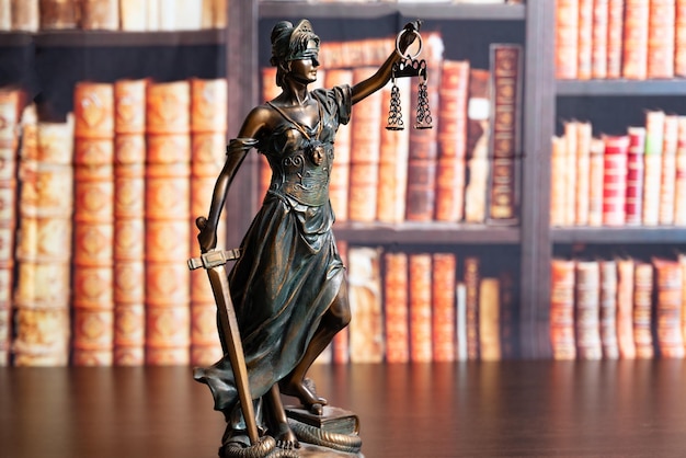 Lawyer office Statue of Justice with scales closeup against the backdrop of a wall of books or a library Legal law advice and justice concept