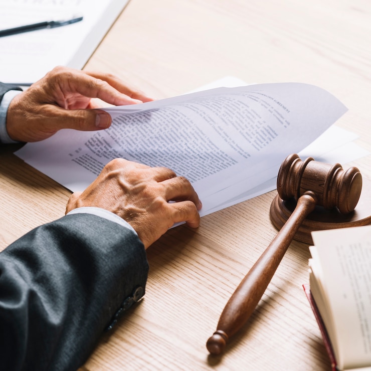 Photo lawyer's hand holding document with gavel and mallet on wooden desk