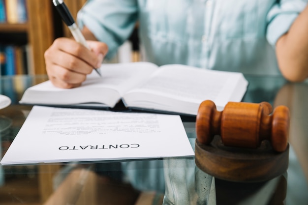 Lawyer sitting with gavel, contract and book at table