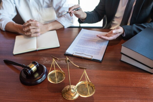 Lawyer working with client discussing contract papers with brass scale