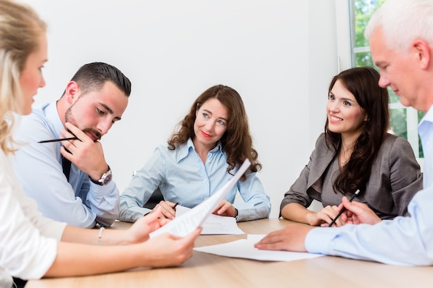 Lawyers having team meeting in law firm reading documents and negotiating agreements