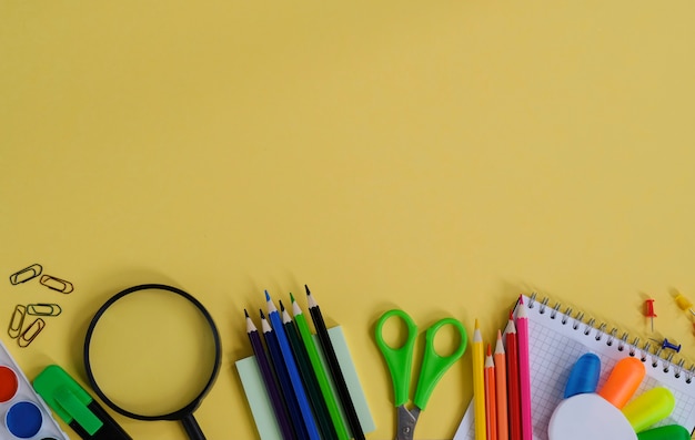 Lay-out met schoolbenodigdheden en kantoorbehoeften op gele achtergrond.