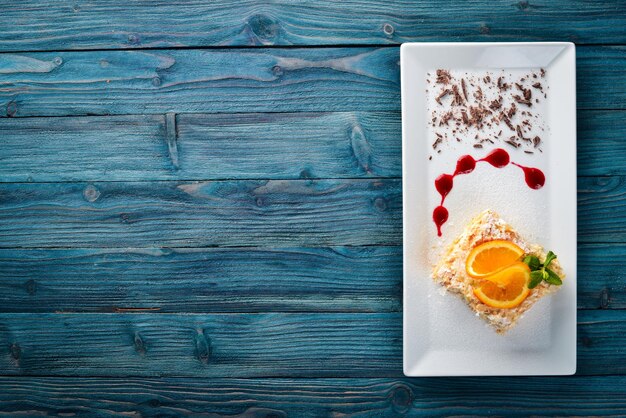 Layered cake with orange flavor On a wooden background Free space for your text Top view