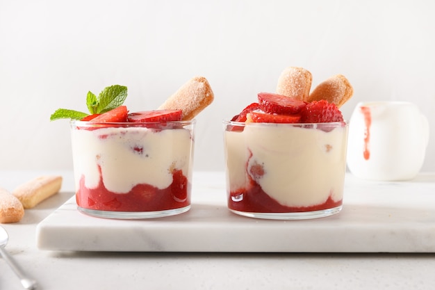 Layered dessert in glass jars with cookie savoyardi mascarpone and whipped cream decorated