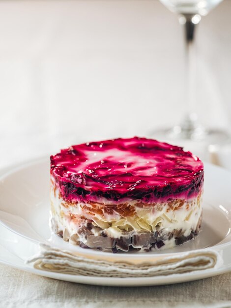 Photo layered salad herring under fur coat on table portion of traditional russian salad with herring beet and other vegetables on white linen tablecloth copy space vertical