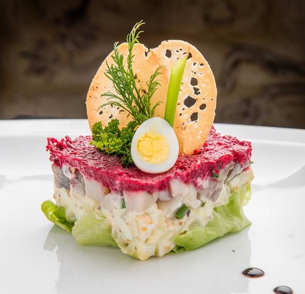 Layered salad with herring, beets, carrots, onions, potatoes and eggs