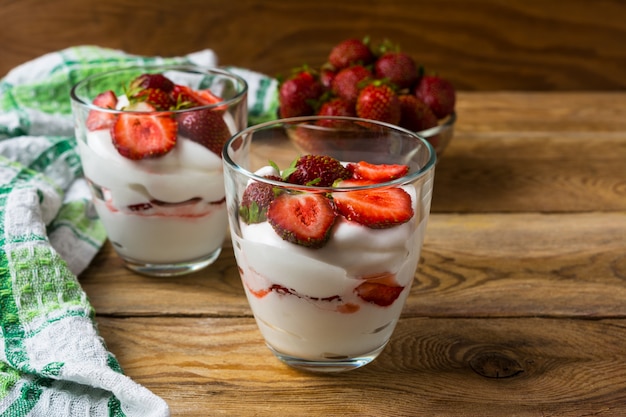 Layered strawberries dessert with cream cheese on rustic wooden background