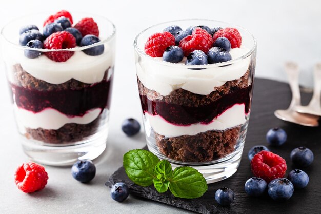 Photo layered trifle dessert with chocolate sponge cake whipped cream berries and fruit jelly in serving