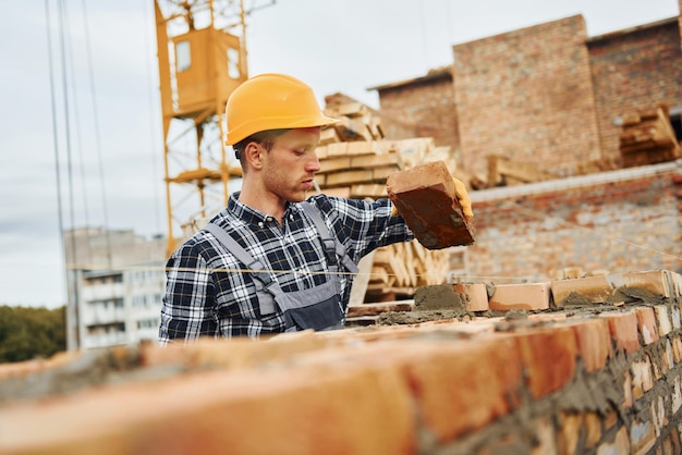 Laying bricks Construction worker in uniform and safety equipment have job on building