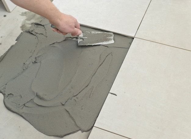 Фото Укладка керамической плитки. затирка бетонного пола перед укладкой белой плитки.