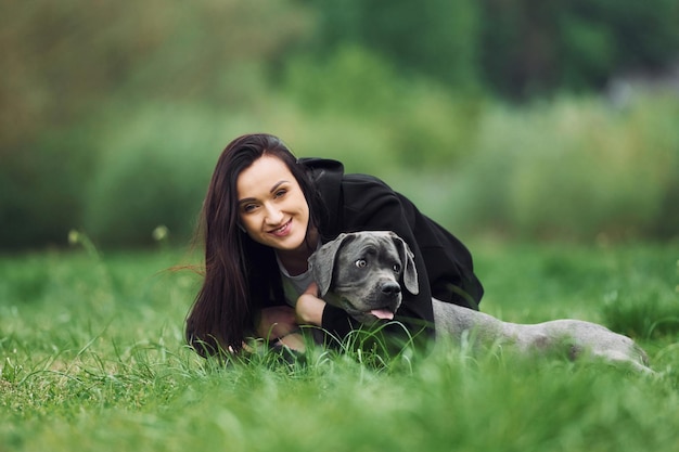 Laying down and smiling Young brunette is having a walk with her dog outdoors