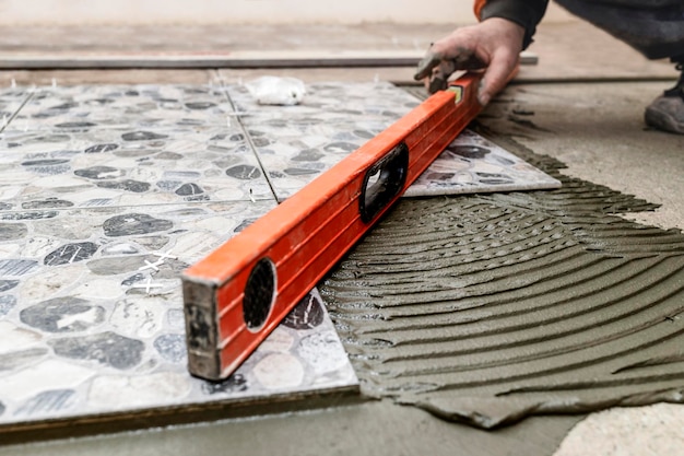 Laying Floor Ceramic Tile. Construction Worker laying tiles over Concrete Floor using Tile Levelers