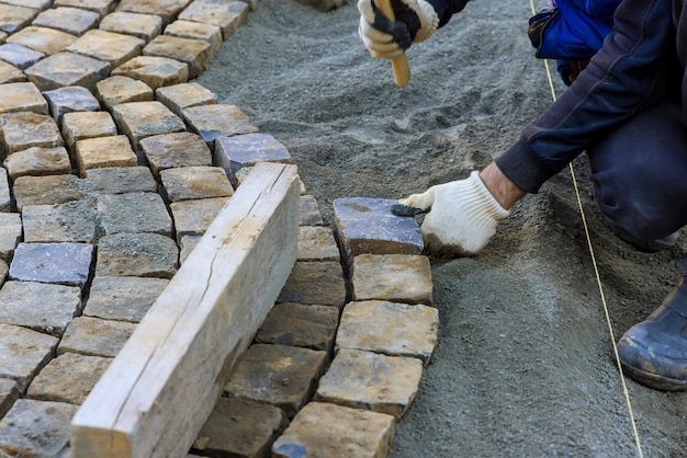 Photo laying granite cubes stone pavement on the a city street with construction worker