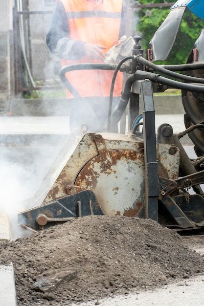 Laying of modern innovative asphalt pavement on city roads with\
the help of special equipment an employee of a road repair company\
works at a roadbed replacement facility