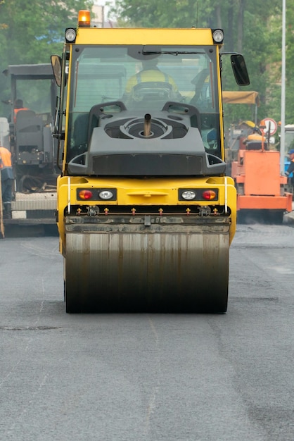 Laying of new modern asphalt Asphalt laying equipment works on the site A yellow asphalt skating rink rides in closeup on a new roadbed