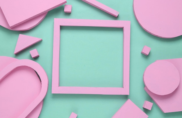 Layout composition of pink geometric shapes and empty frame for copy space on blue background Flat lay