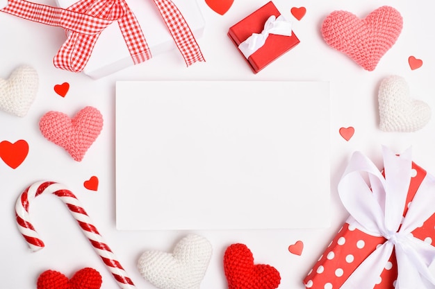 Layout of an invitation to a romantic meeting. Background for a copy space for Valentine's Day with gifts and knitted hearts. Flat position, top view