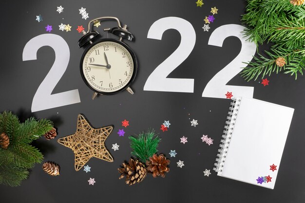 写真 暗い背景にクリスマスツリーの数字、時計、おもちゃ、枝を使って、2022年の新年をテーマにしたレイアウト。