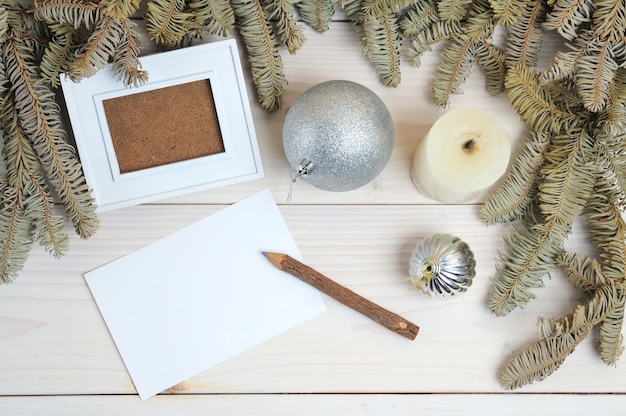 Layout of a photo frame, paper, pencil on a Christmas theme on a white wooden surface