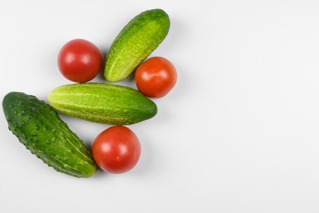 Layout of ripe tomatoes and cucumbers on a white background the concept of cooking organic vegetable