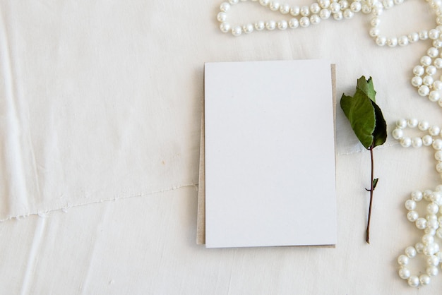 Layout scene of a stationery layout An empty vertical greeting card a string of pearls and dried flowers isolated on a white table background Top view blank for invitation