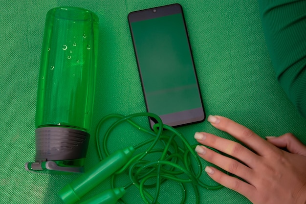 Layout of things for sports, sports equipment on a green background, jump rope, water bottle