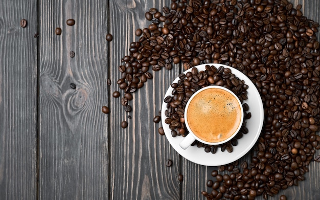 Layout, white cup with espresso coffee and grains on a wooden dark table