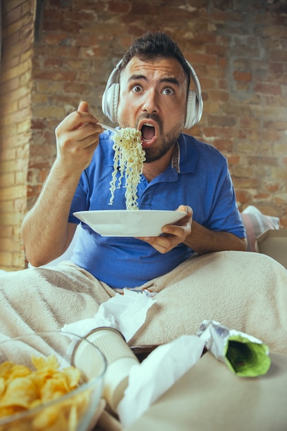 Lazy man living the whole life in his bed surrounded with\
messy