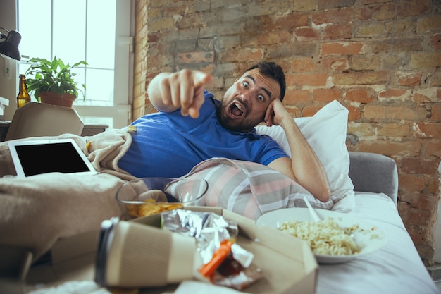 Lazy man livingin his bed surrounded with messy