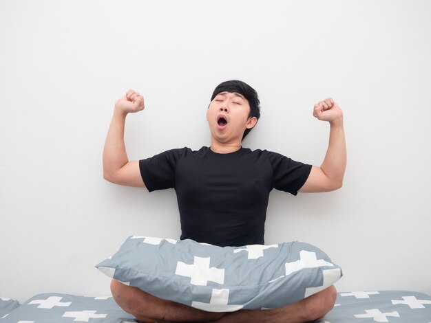 Lazy Man sit on the bed with pillow feeling sleepy and yawn