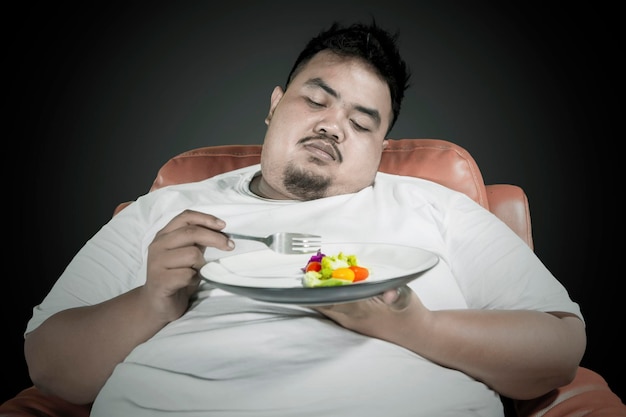 Lazy overweight man eats healthy food