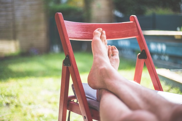 Lazy time at home in the own garden resting feet and legs on a\
red chair