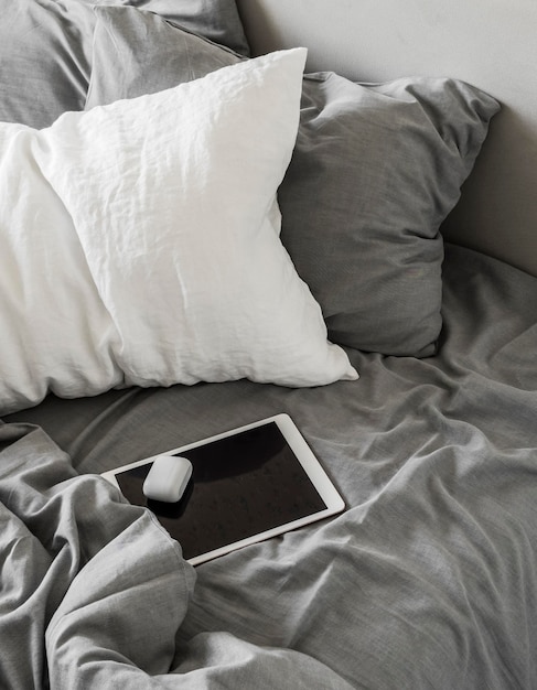 Lazy weekend concept Tablet in a bed top view Scandinavian style bedroom