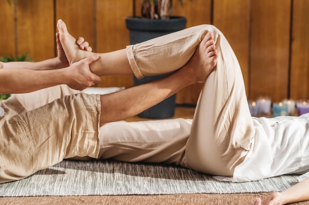 Foto yoga pigro massaggio thailandese parte inferiore del corpo stretching passivo dell'anca e della gamba