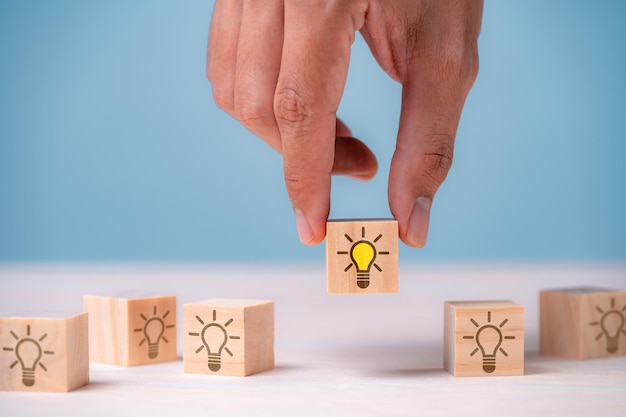 Leader choosing the best new idea with light bulb icon on wooden blocks Explore creative design solutions strategy reviews Inspiring innovation and teamwork