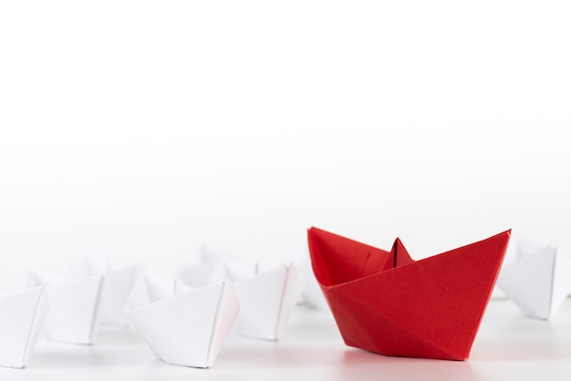 Leadership concept. red paper ship lead among white