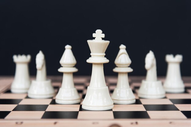 Концепция лидерства Белые шахматные фигуры на черном фоне