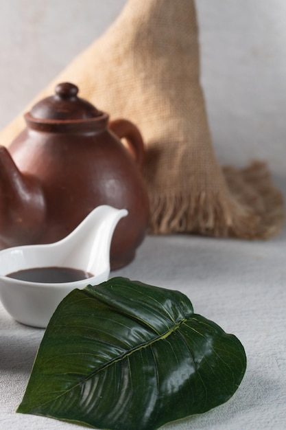 Leaf for decoration with sweet soy sauce on a white spoon and jug on white table