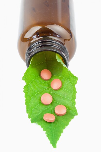 Leaf and pills in a small bottle